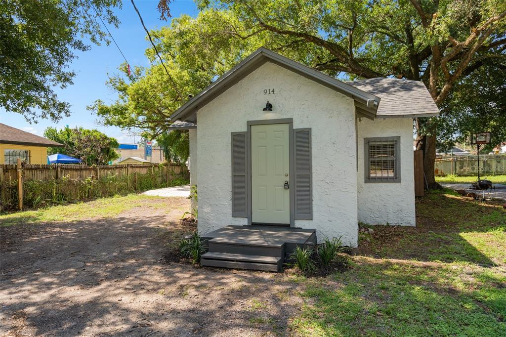 A small, white stucco detached building with a light green door and gray shutters — 914 26TH STREET, ORLANDO, FL