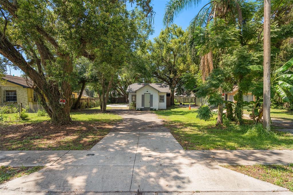 A small, light-colored house sits at the end of a long driveway surrounded by trees — 914 26TH STREET, ORLANDO, FL