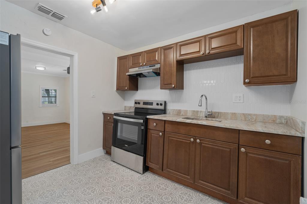 A kitchen features wood cabinets, a stainless steel stove, a sink, and patterned tile flooring — 914 26TH STREET, ORLANDO, FL