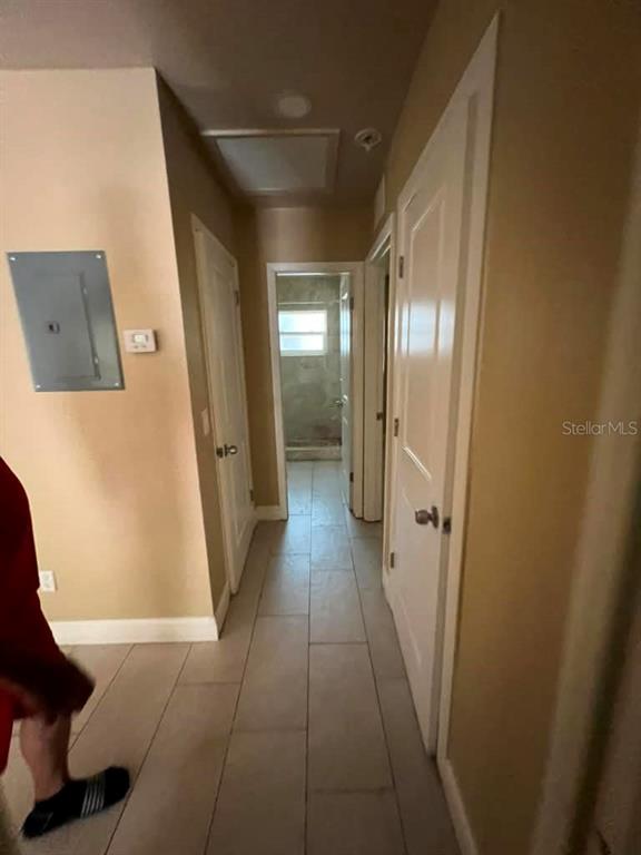 A hallway with light-colored tile flooring leads to a bathroom with a window — 10106 N 10TH STREET UNIT A, TAMPA, FL
