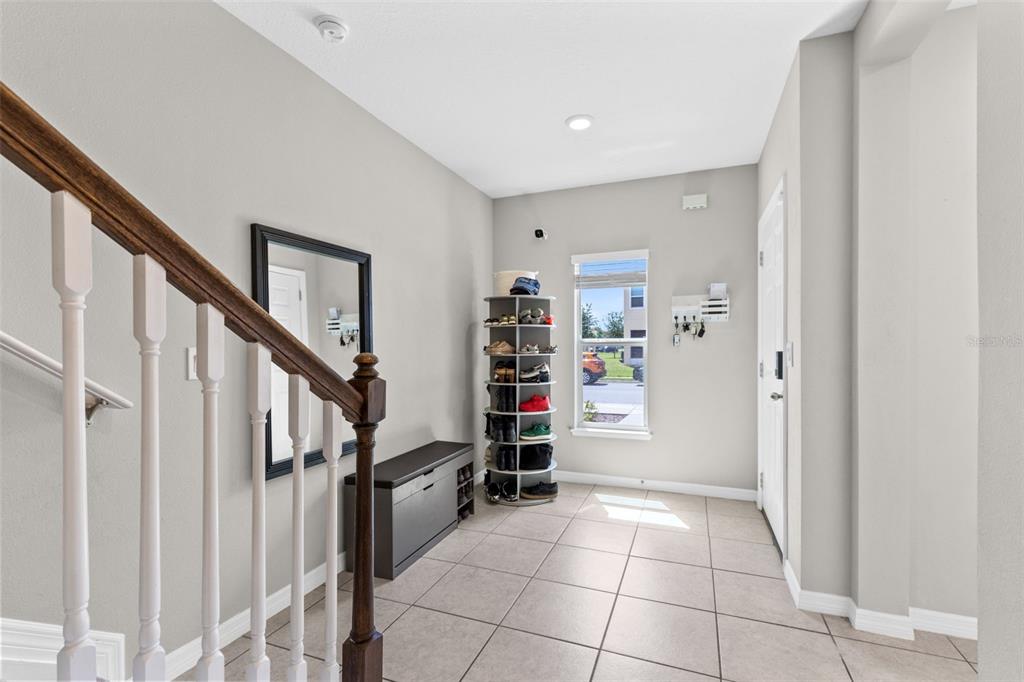 An entryway features a staircase, a shoe rack, a storage bench, and tile flooring — 4827 CORAL CASTLE DRIVE, KISSIMMEE, FL