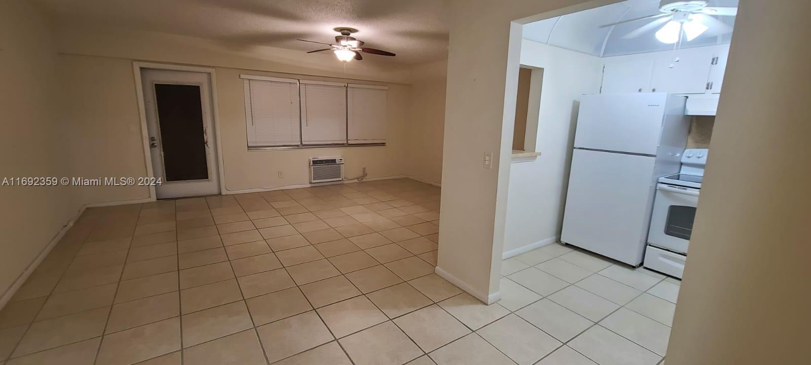 A tiled living area connects to a kitchen featuring white appliances and cabinets — 34 Mansfield A # 34, Boca Raton FL 33434, BOCA RATON, FL
