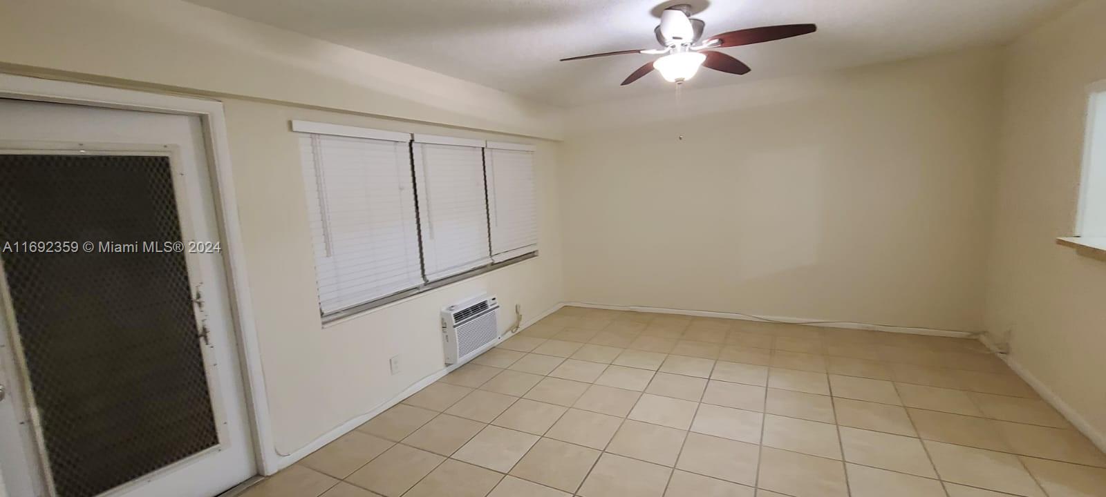 An empty room features beige tile flooring, a ceiling fan, and a wall-mounted air conditioner — 34 Mansfield A # 34, Boca Raton FL 33434, BOCA RATON, FL