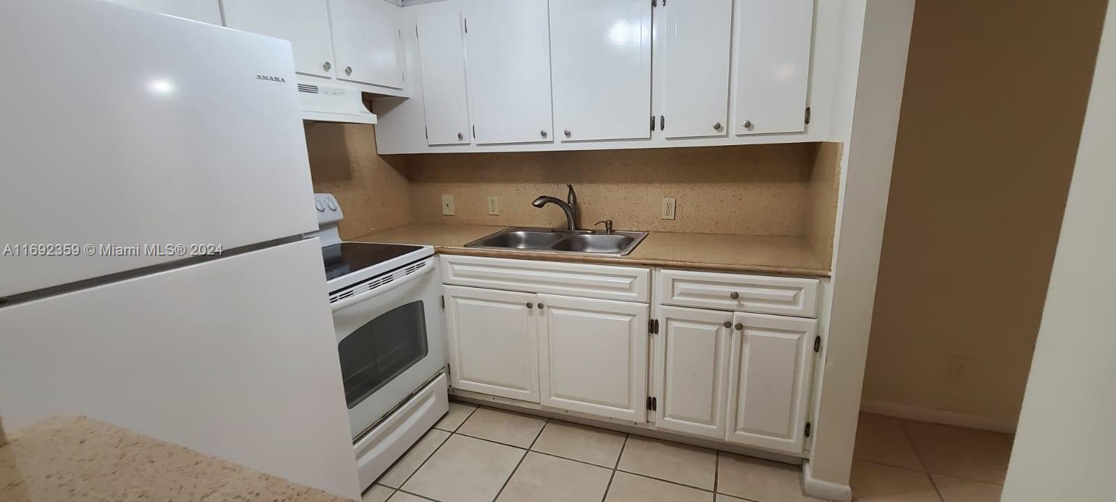 A kitchen features white cabinets, a stainless steel sink, and white appliances — 34 Mansfield A # 34, Boca Raton FL 33434, BOCA RATON, FL