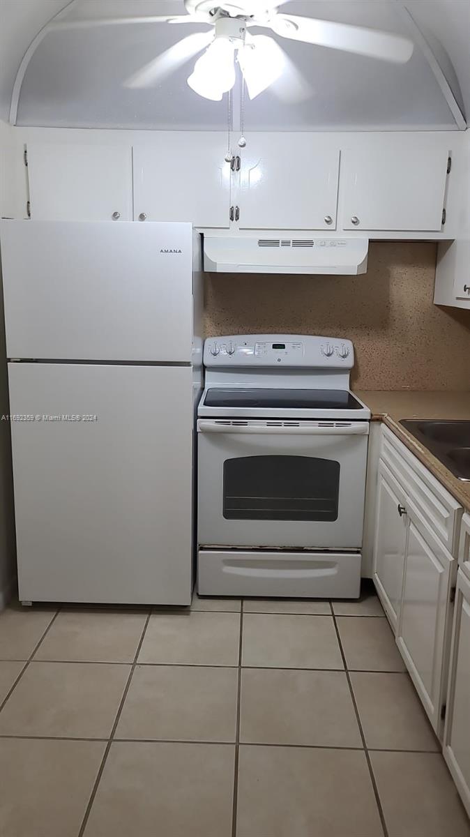 A white kitchen features a refrigerator, electric range, and white cabinetry above a tiled floor — 34 Mansfield A # 34, Boca Raton FL 33434, BOCA RATON, FL
