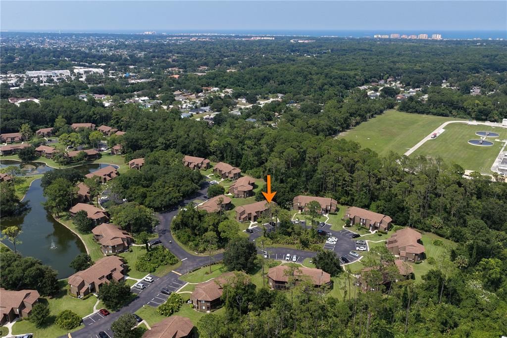 An aerial view shows a multi-unit residential complex surrounded by trees and a small pond — 37 HEMBURY LANE UNIT 37, PALM COAST, FL