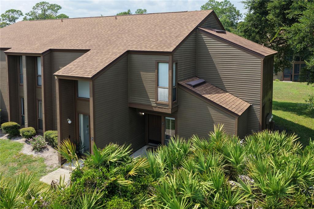 An exterior view of a two-story brown wood-sided townhouse with a shingled roof — 37 HEMBURY LANE UNIT 37, PALM COAST, FL