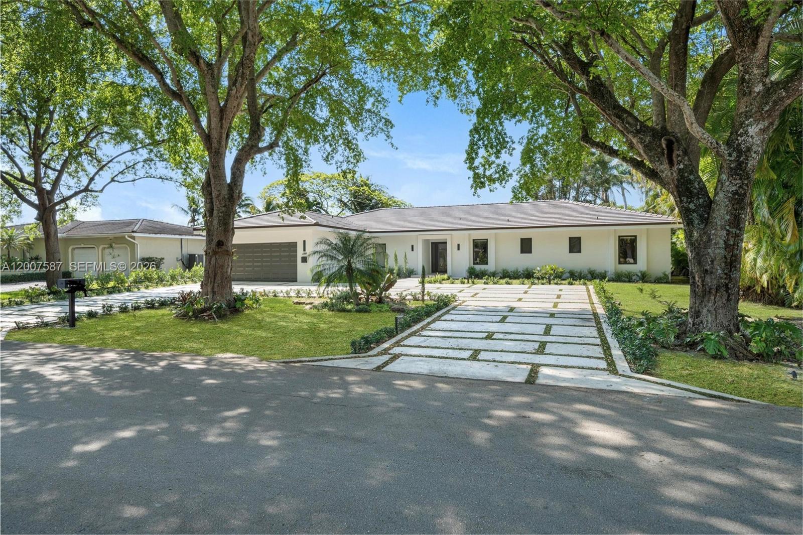 A single-story white house with a paved driveway and large trees in the front yard — 1520 Lugo Ave, Coral Gables FL 33156, CORAL GABLES, FL