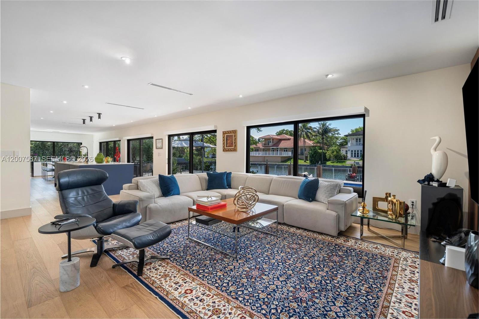 A living room features a large sectional sofa, a patterned rug, and floor-to-ceiling windows — 1520 Lugo Ave, Coral Gables FL 33156, CORAL GABLES, FL