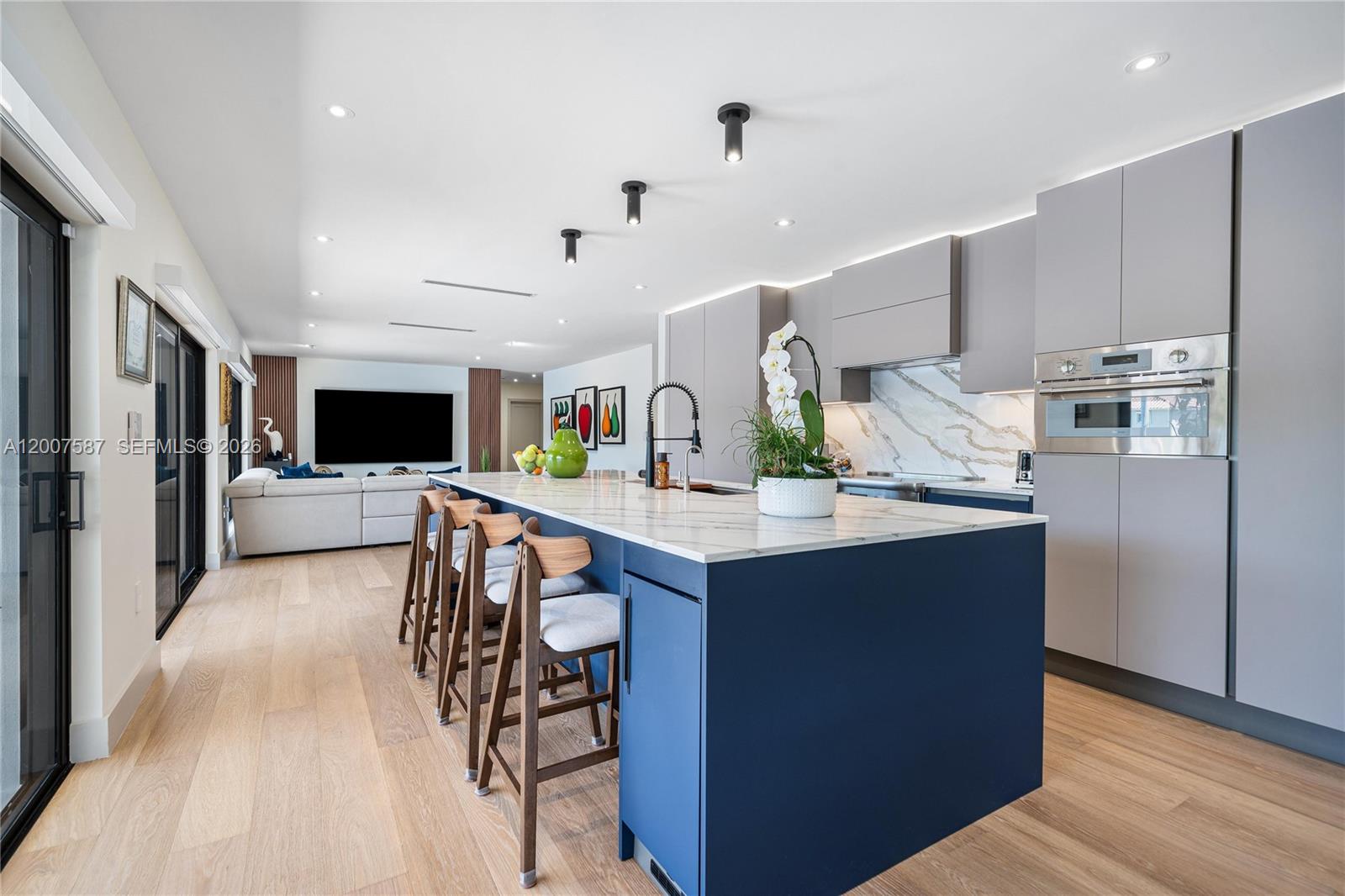 A modern kitchen features a blue island with bar stools and light gray cabinetry — 1520 Lugo Ave, Coral Gables FL 33156, CORAL GABLES, FL