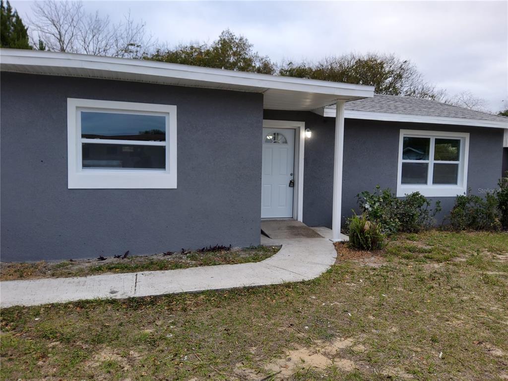 A gray, single-story house with a white front door and a concrete walkway — 415 KING STREET, LAKE WALES, FL
