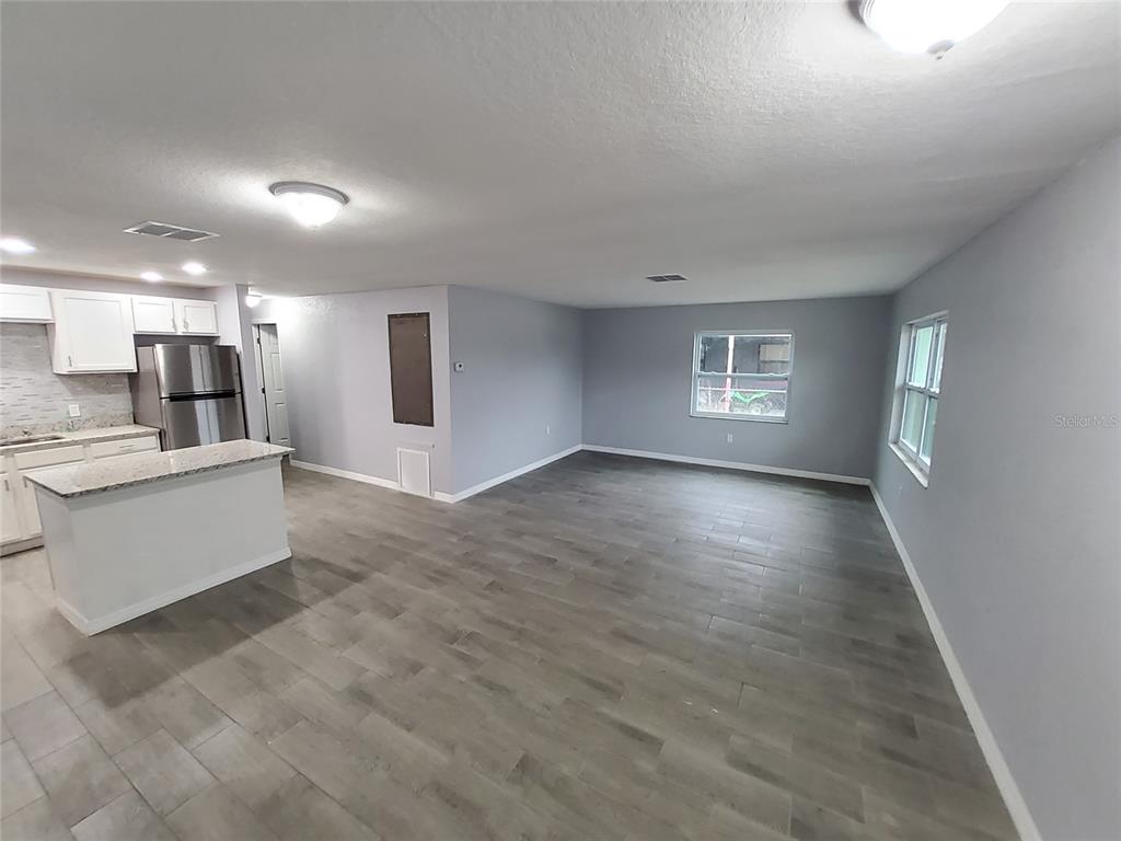 An open-concept kitchen and living area features gray wood-look flooring and white cabinetry — 415 KING STREET, LAKE WALES, FL