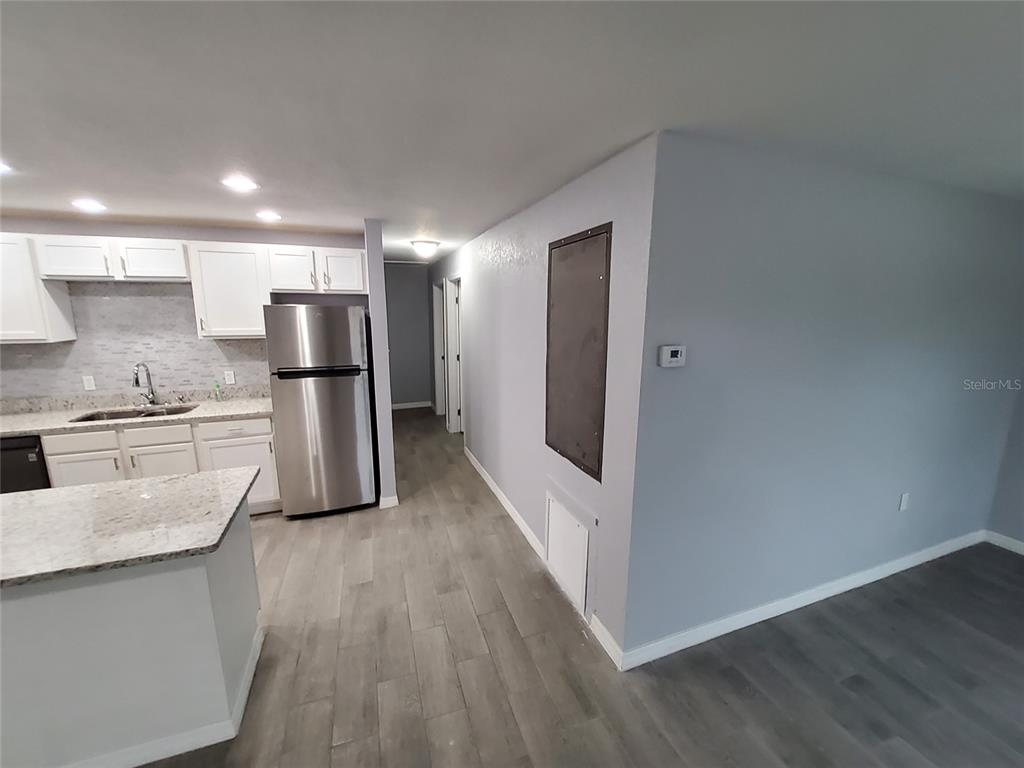 A kitchen with white cabinets and stainless steel appliances opens to a hallway and living area — 415 KING STREET, LAKE WALES, FL