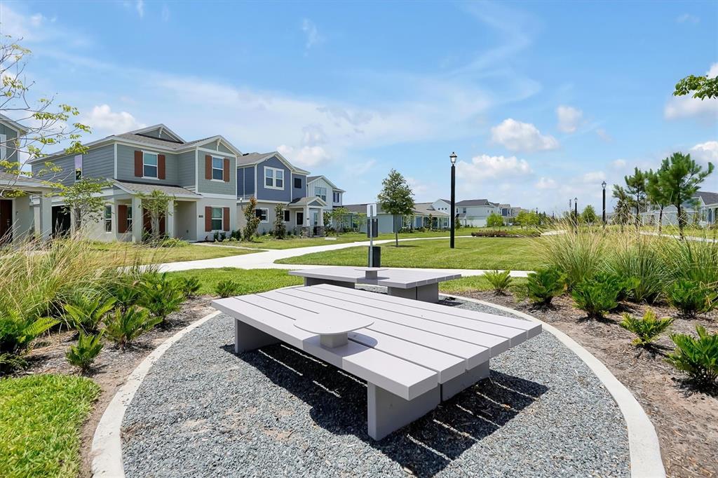 A gray outdoor picnic table sits on a gravel pad in front of suburban houses — 7245 SIENNA OAK ALLEY, ORLANDO, FL