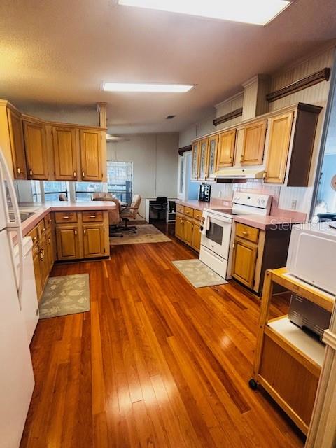 A kitchen with wood cabinets, hardwood floors, and a white stove in a bright space — 7053 SPANISH MOSS LANE, BROOKSVILLE, FL