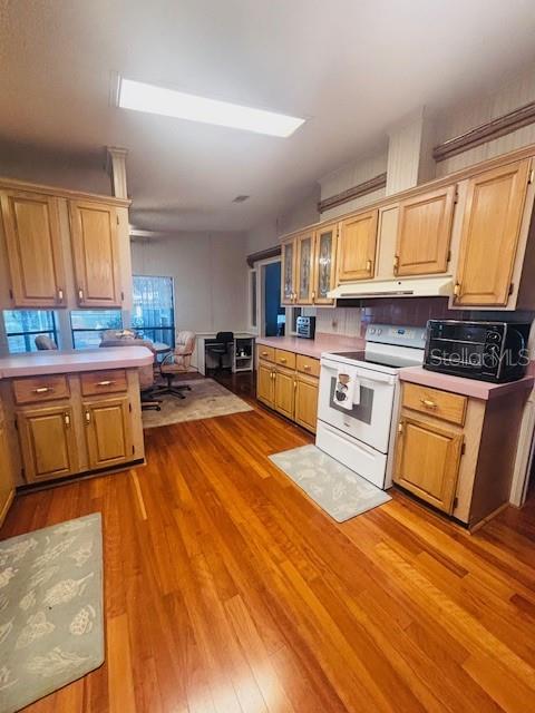 A kitchen features wood cabinets, pink countertops, hardwood floors, and a white stove — 7053 SPANISH MOSS LANE, BROOKSVILLE, FL