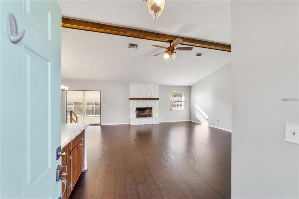 A view from a doorway into a living room with dark wood floors and a fireplace — 2700 SE 35TH STREET, OCALA, FL