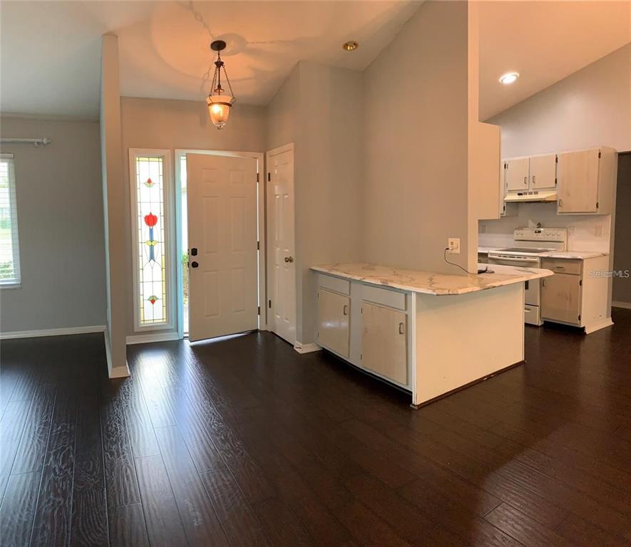 An entryway with dark wood floors leads into a kitchen with white cabinets and countertops — 2700 SE 35TH STREET, OCALA, FL