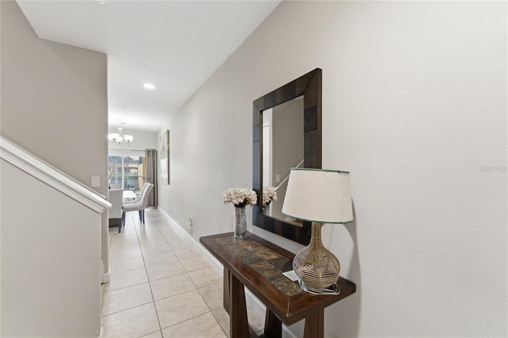 A hallway features a tile floor, a wooden console table with a lamp, and a mirror — 3045 BEACH PALM AVENUE, KISSIMMEE, FL