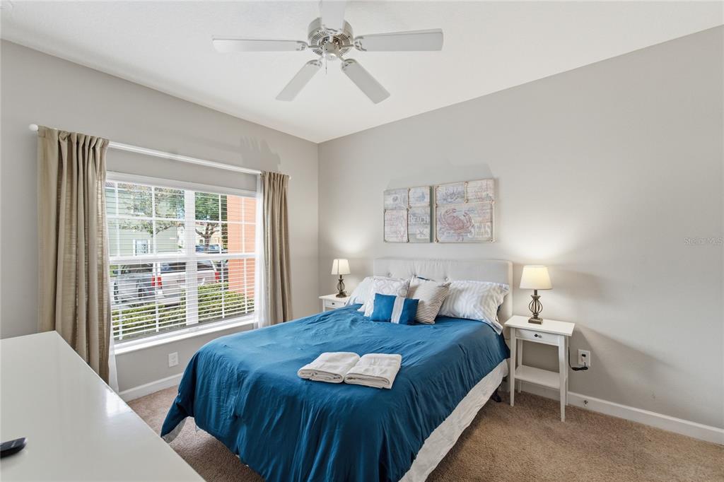 A bedroom features a bed with a blue comforter, two nightstands, and a ceiling fan — 3045 BEACH PALM AVENUE, KISSIMMEE, FL