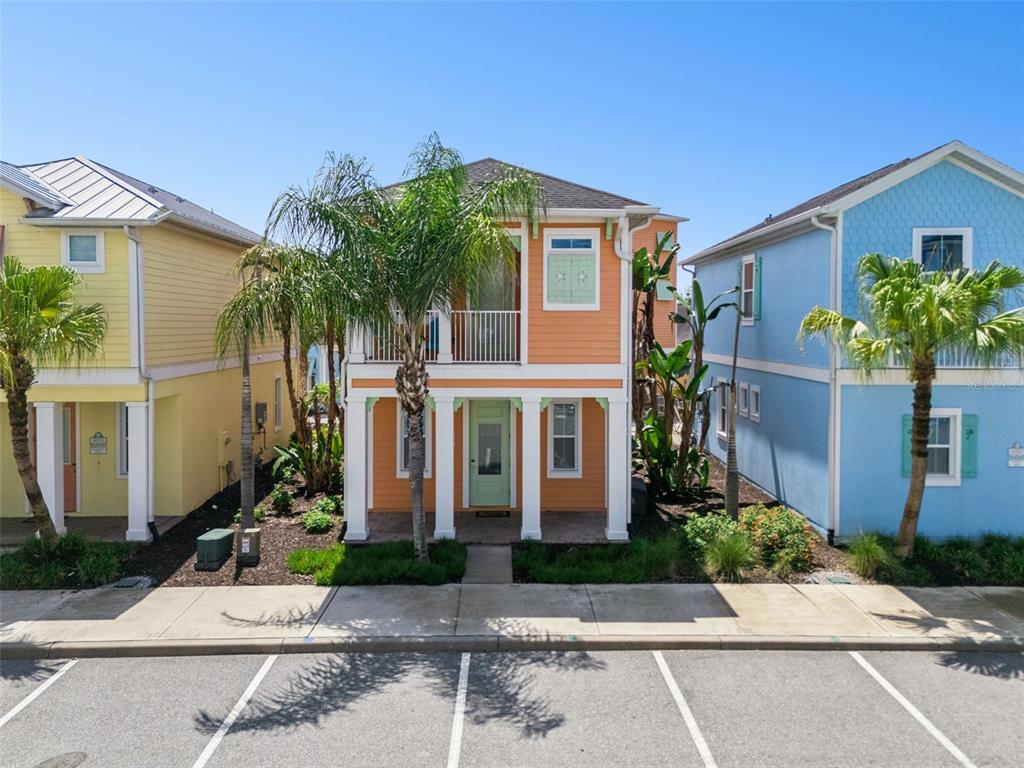 A two-story orange house with a front porch, balcony, and palm trees in the yard — 3071 KEY LIME LOOP, KISSIMMEE, FL