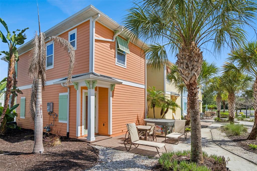 A two-story orange house with a front porch and balcony sits between two colorful homes — 3071 KEY LIME LOOP, KISSIMMEE, FL