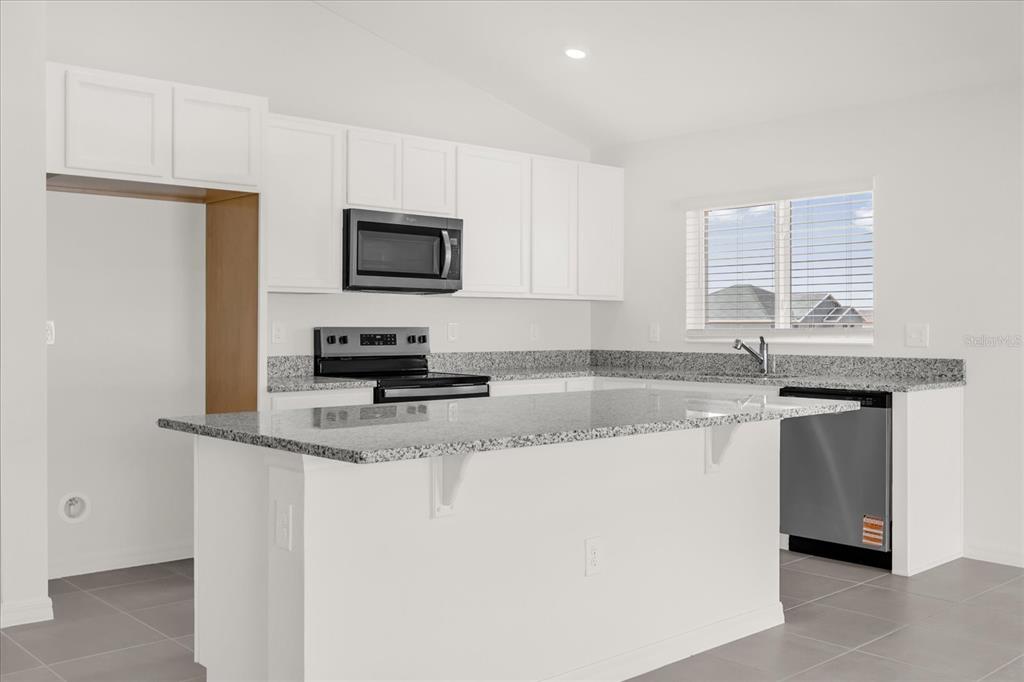 A kitchen with white cabinets, granite countertops, stainless steel appliances, and a central island — 316 SUNBROOK DRIVE, GROVELAND, FL