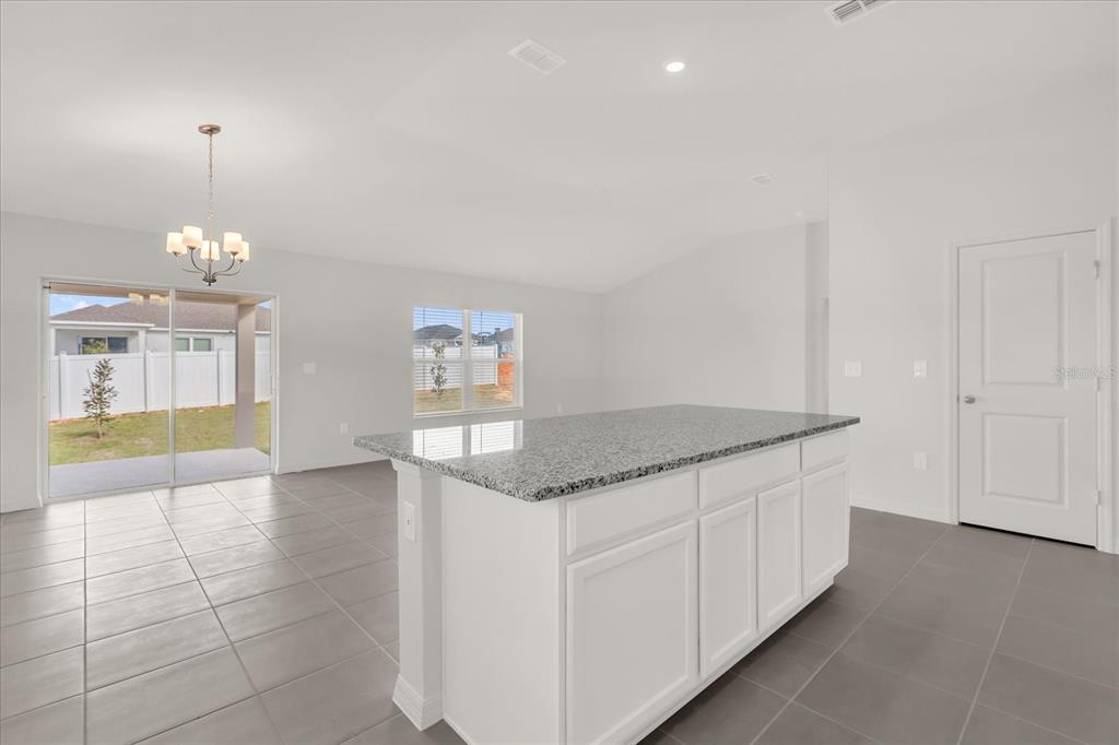 A kitchen island with granite countertops sits in a room with gray tile flooring — 316 SUNBROOK DRIVE, GROVELAND, FL