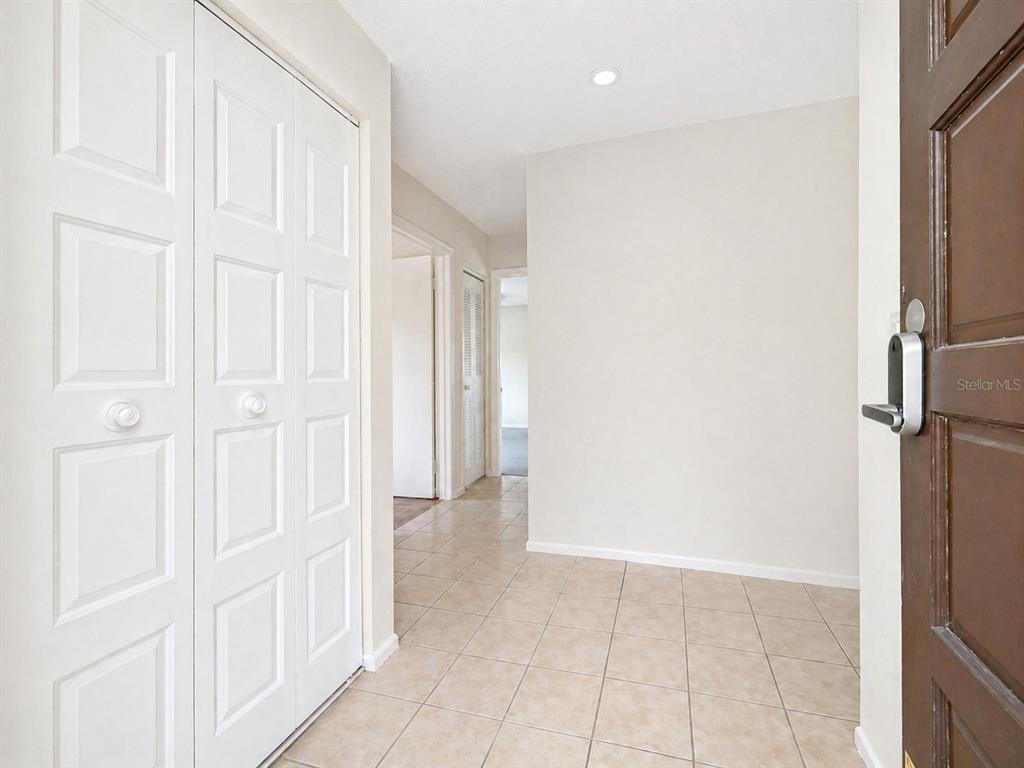 An entryway features tile flooring, a white closet with paneled doors, and a brown door — 723 115TH AVENUE N UNIT 2106, ST PETERSBURG, FL
