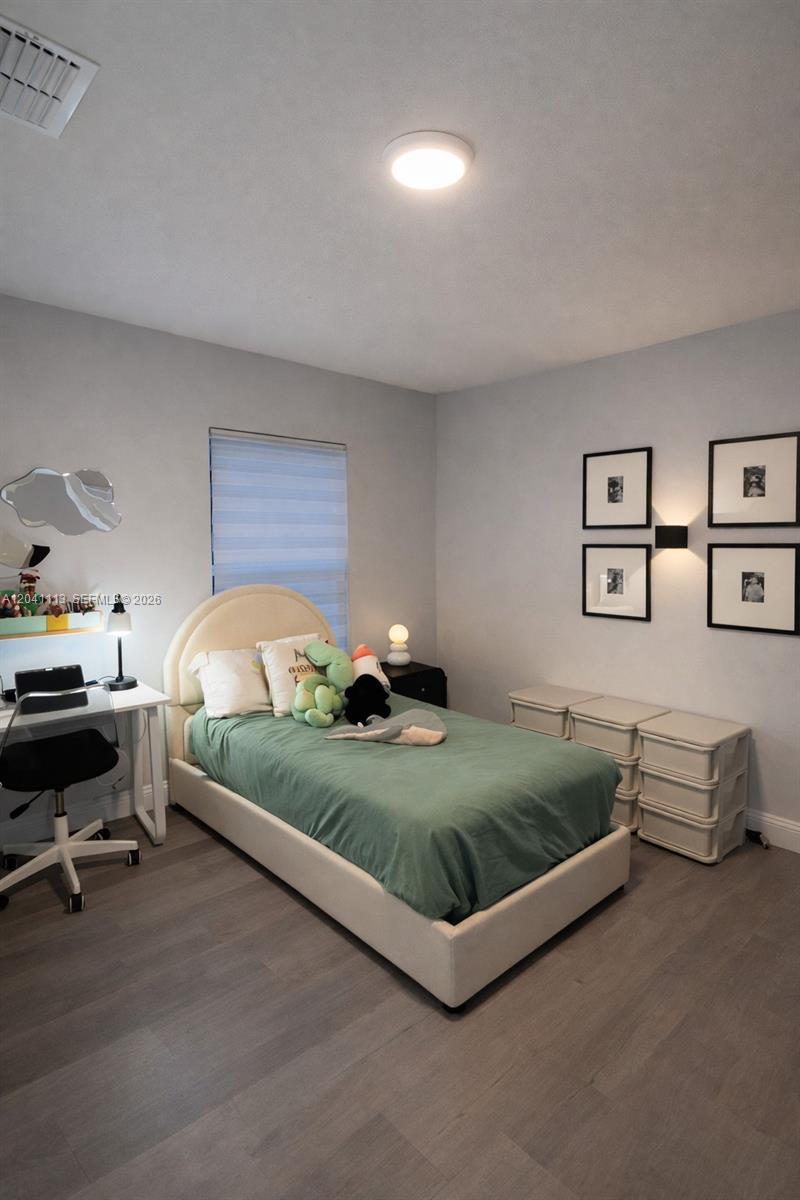A bedroom features a bed with a green quilt, a desk, and wall-mounted framed art — 39 REDWOOD TRACK RUN, Ocala FL 34472, OCALA, FL