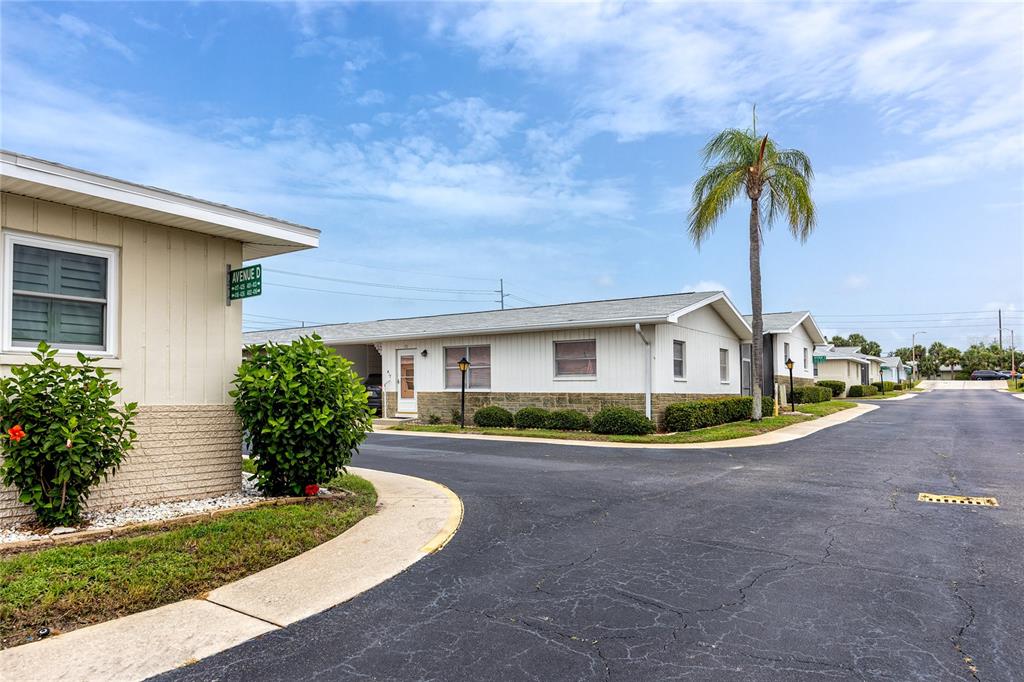 A street view of single-story residential buildings with white siding and a palm tree — 12400 PARK BOULEVARD UNIT 417, SEMINOLE, FL