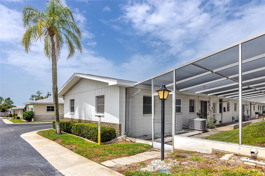 A white single-story building with a screened-in patio and a tall palm tree outside — 12400 PARK BOULEVARD UNIT 417, SEMINOLE, FL