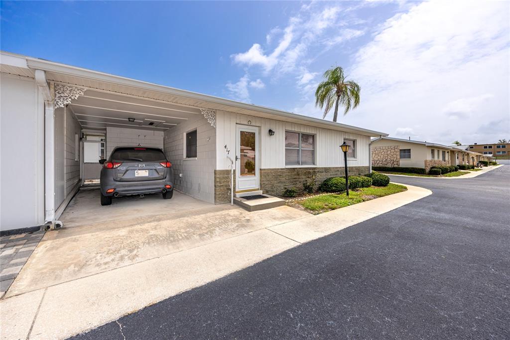 A single-story residence features a carport, a gray car, and a stone-accented exterior facade — 12400 PARK BOULEVARD UNIT 417, SEMINOLE, FL
