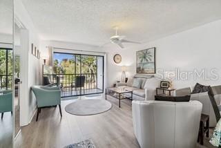 A living room features light wood flooring, a ceiling fan, and a sliding glass balcony door — 104 E CYPRESS COURT UNIT 104, OLDSMAR, FL