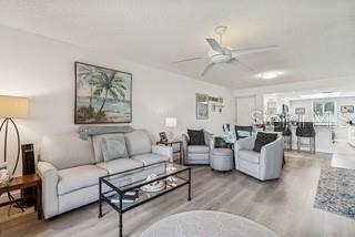 A living room features a light gray sofa, two armchairs, a glass coffee table, and flooring — 104 E CYPRESS COURT UNIT 104, OLDSMAR, FL