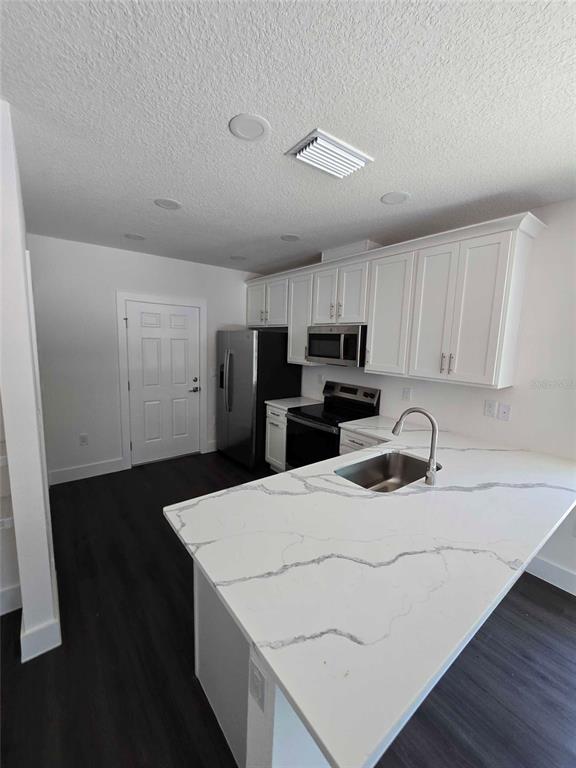 A kitchen features white cabinets, stainless steel appliances, and a white quartz island countertop — 18082 PARAKEET ROAD, WEEKI WACHEE, FL