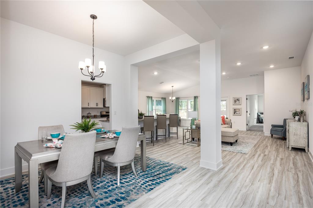 A dining area with a blue rug opens into a living room and kitchen space — 16929 NW 176TH WAY, ALACHUA, FL