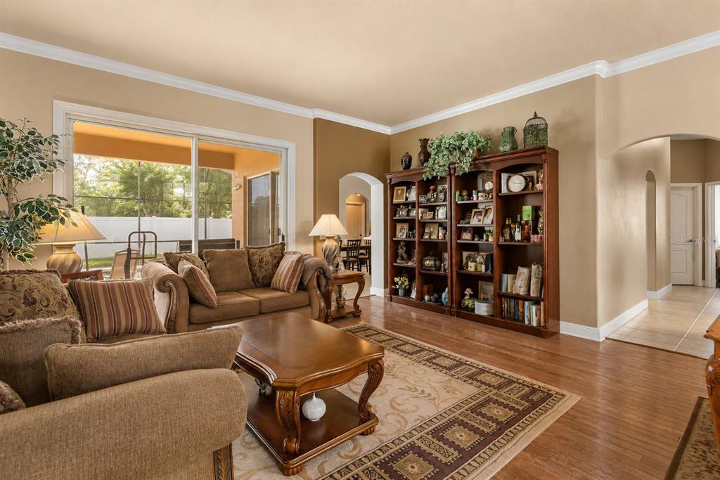 A living room with wood flooring, a large wooden bookshelf, and a sliding glass door — 631 WATERLAND COURT, ORLANDO, FL