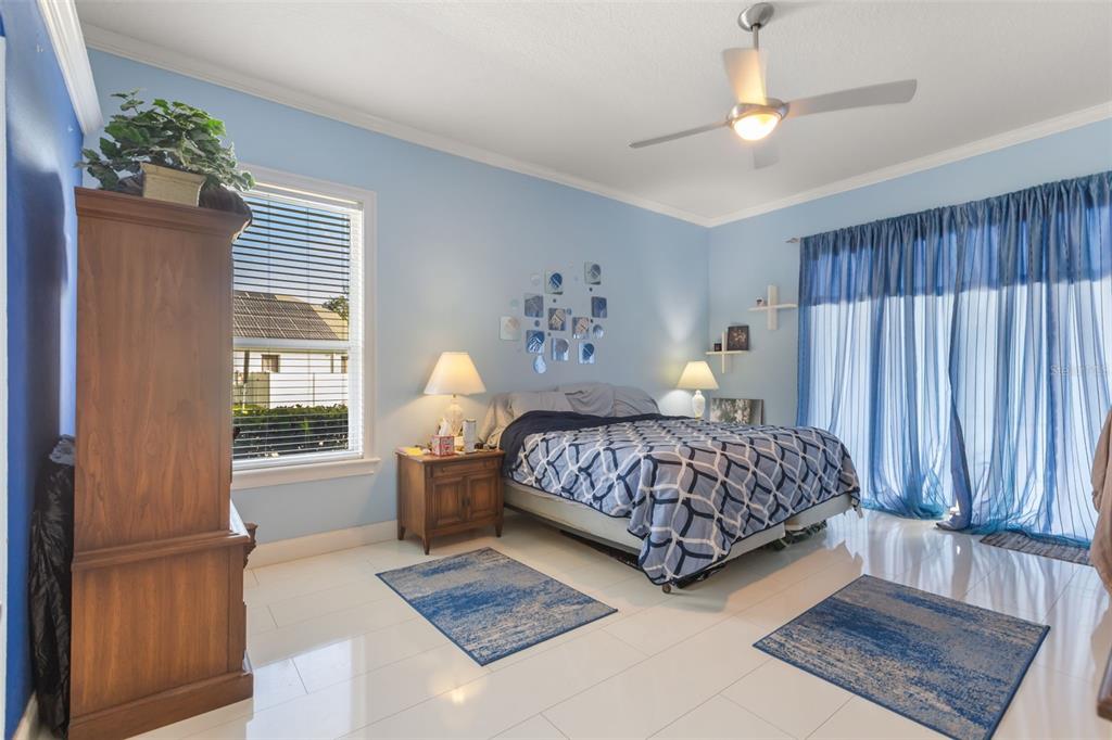 A bedroom with light blue walls, a patterned bedspread, white tile floors, and blue curtains — 631 WATERLAND COURT, ORLANDO, FL