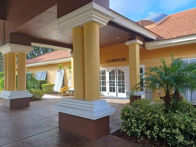 The exterior of a clubhouse features yellow columns, a tiled roof, and a glass entrance — 3005 RED GINGER ROAD, KISSIMMEE, FL