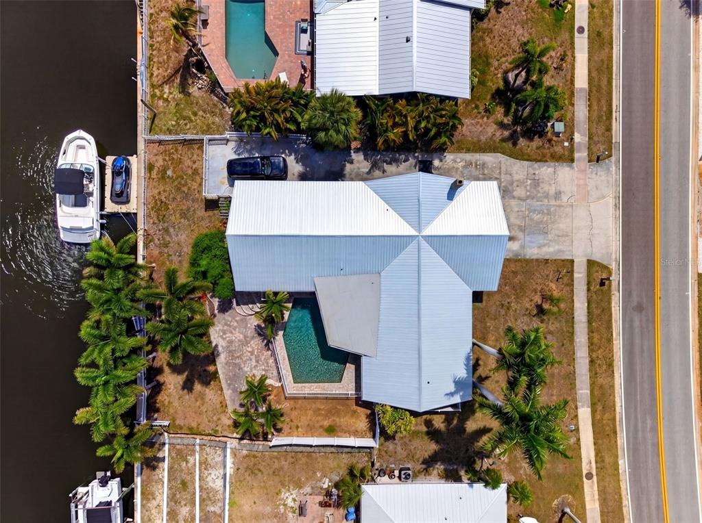 An aerial view shows a waterfront house with a metal roof, pool, and boat dock — 2555 CONSTITUTION BOULEVARD, SARASOTA, FL