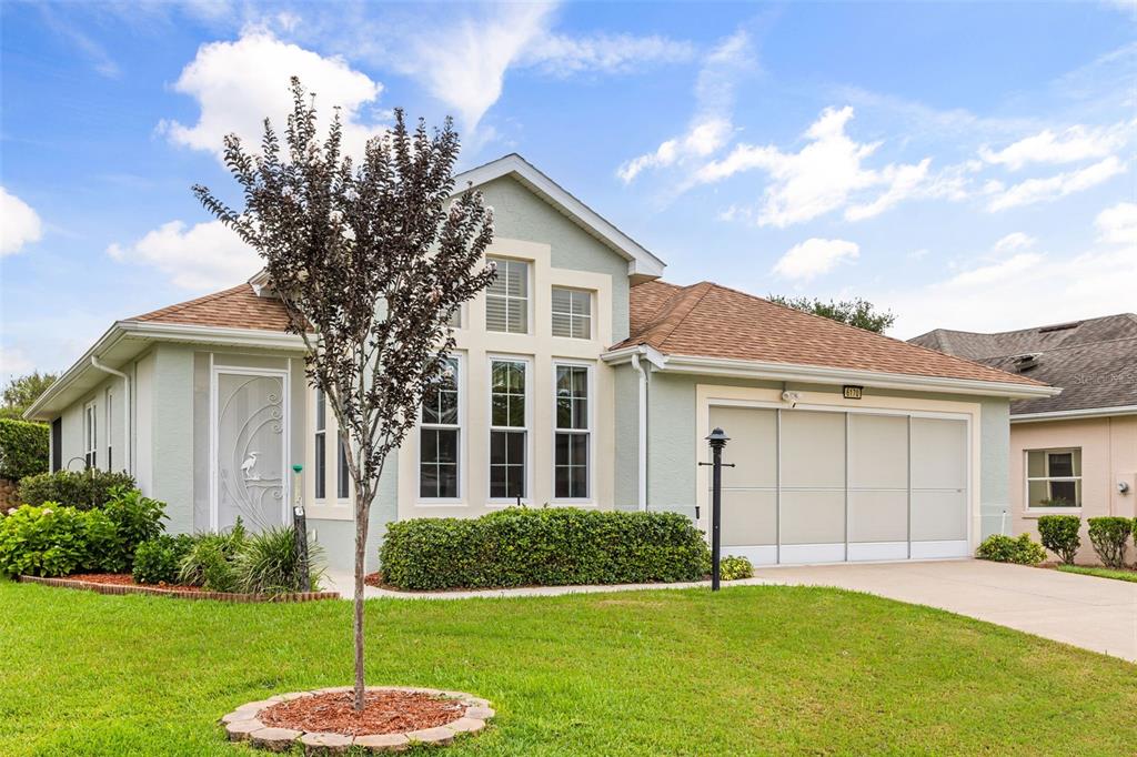 A light green single-story house features a multi-pane window, a garage, and a front lawn — 6170 SAILBOAT AVENUE, TAVARES, FL