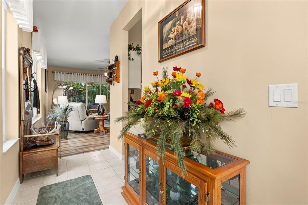 A hallway with tile flooring leads to a living area featuring a wooden display cabinet — 6170 SAILBOAT AVENUE, TAVARES, FL
