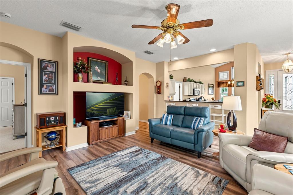 A living room features a blue sofa, a white armchair, and a built-in media niche — 6170 SAILBOAT AVENUE, TAVARES, FL