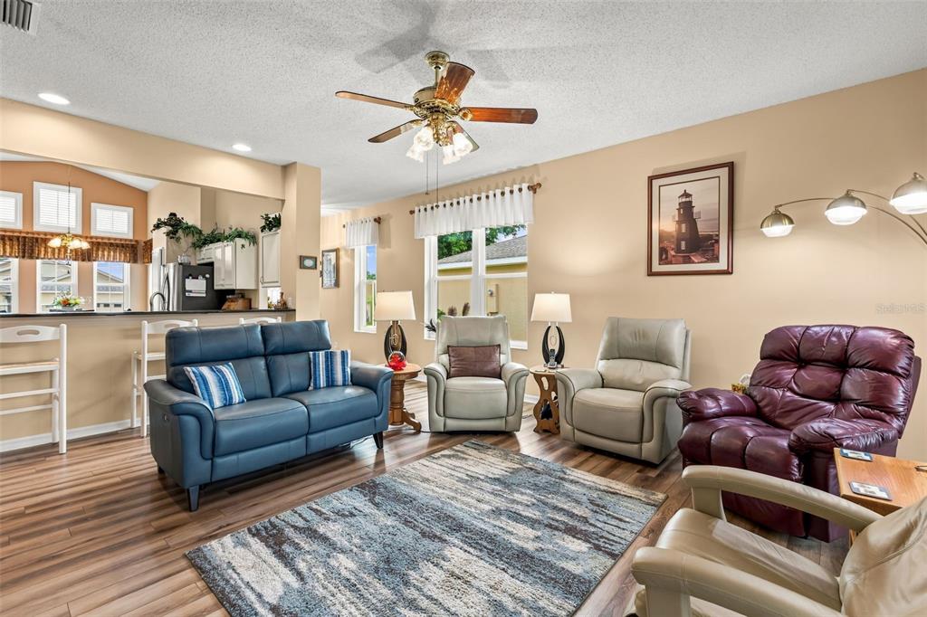 A living room with a blue sofa, three armchairs, wood flooring, and a ceiling fan — 6170 SAILBOAT AVENUE, TAVARES, FL
