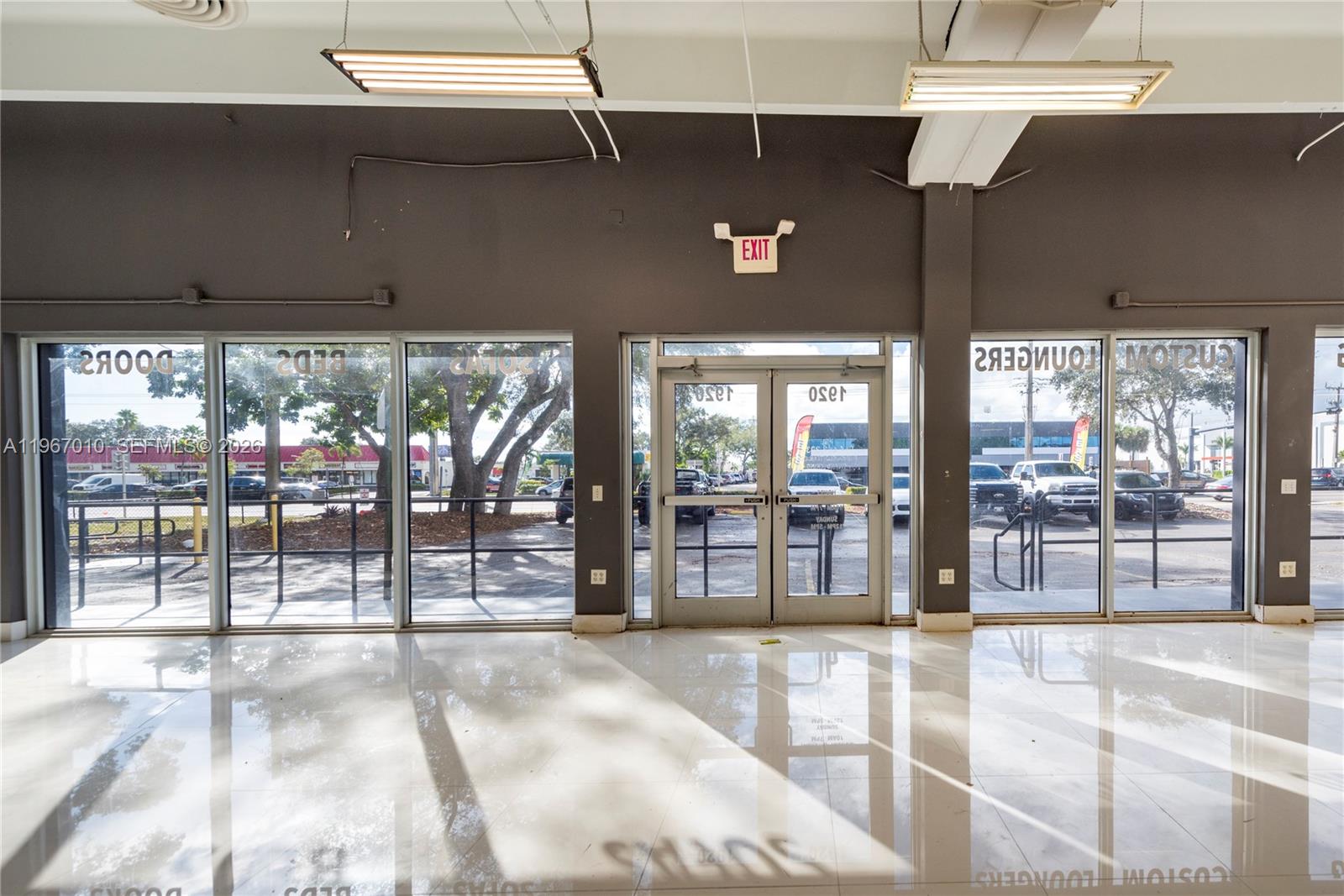 A bright, empty commercial space features large glass windows, double entry doors, and tiled floors — 1920-1936 Stirling Rd, Dania Beach FL 33004, DANIA BEACH, FL