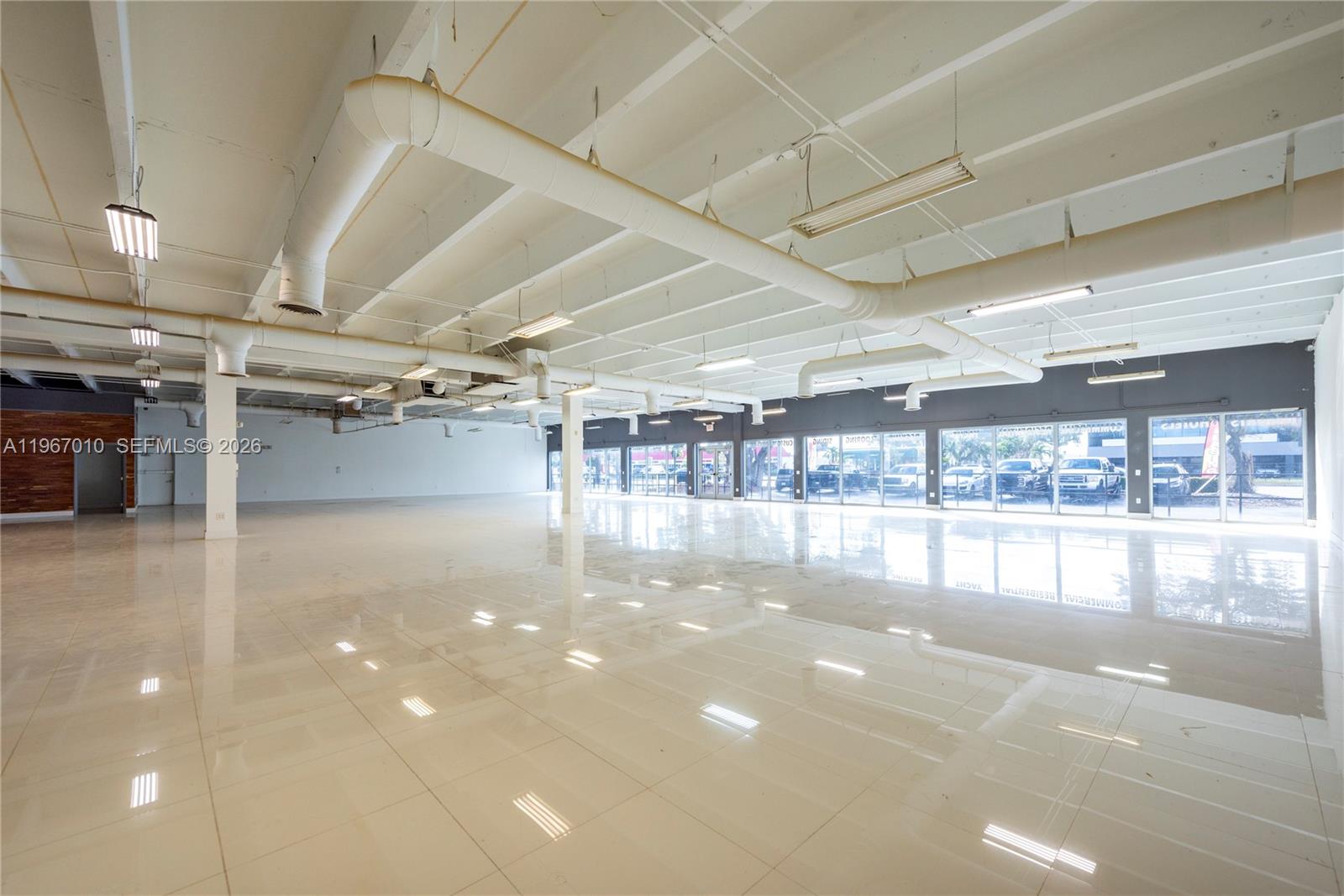 A large, open commercial space features white tiled floors, exposed ceiling beams, and floor-to-ceiling windows — 1920-1936 Stirling Rd, Dania Beach FL 33004, DANIA BEACH, FL