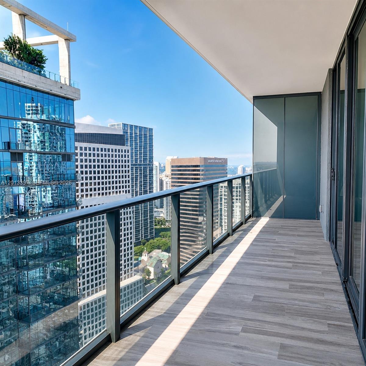 A high-rise balcony with wood-look tile flooring overlooks a dense urban skyline — 801 S Miami Ave # 4206, Miami FL 33130, MIAMI, FL