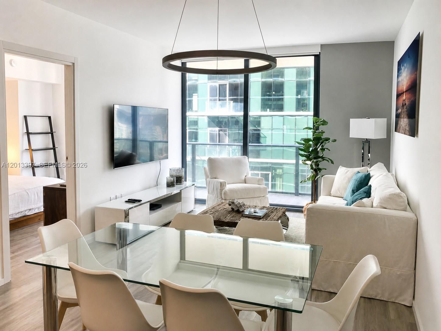 A modern living and dining area features a glass table, white sofa, and floor-to-ceiling windows — 801 S Miami Ave # 4206, Miami FL 33130, MIAMI, FL