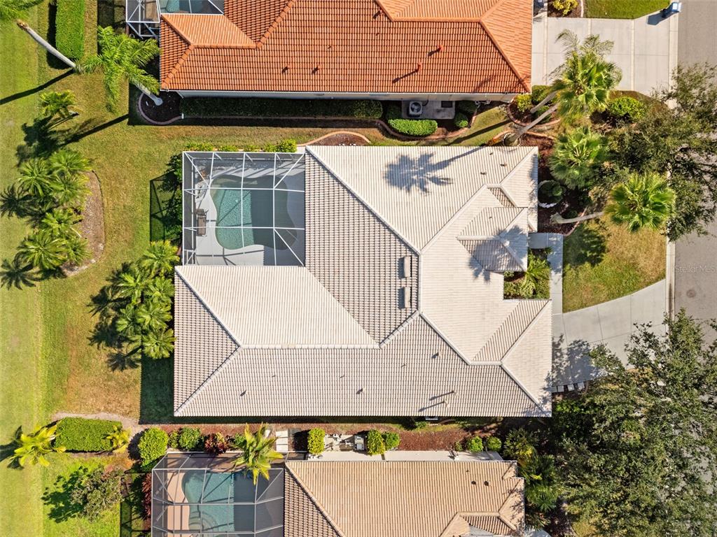 An aerial view shows a house with a tiled roof, a screened pool, and landscaping — 6882 TAILFEATHER WAY, BRADENTON, FL